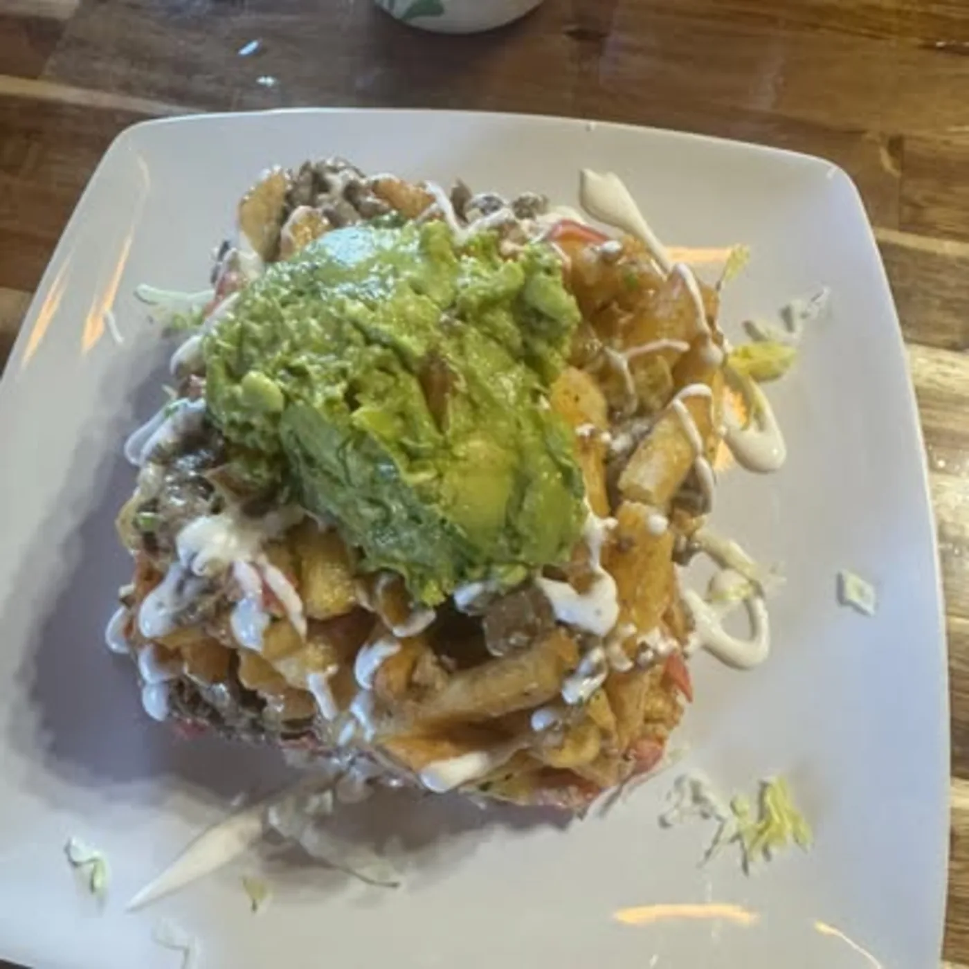 Loaded chilaquiles-style plate with guacamole, crema, and fresh toppings at Nina's Tacos