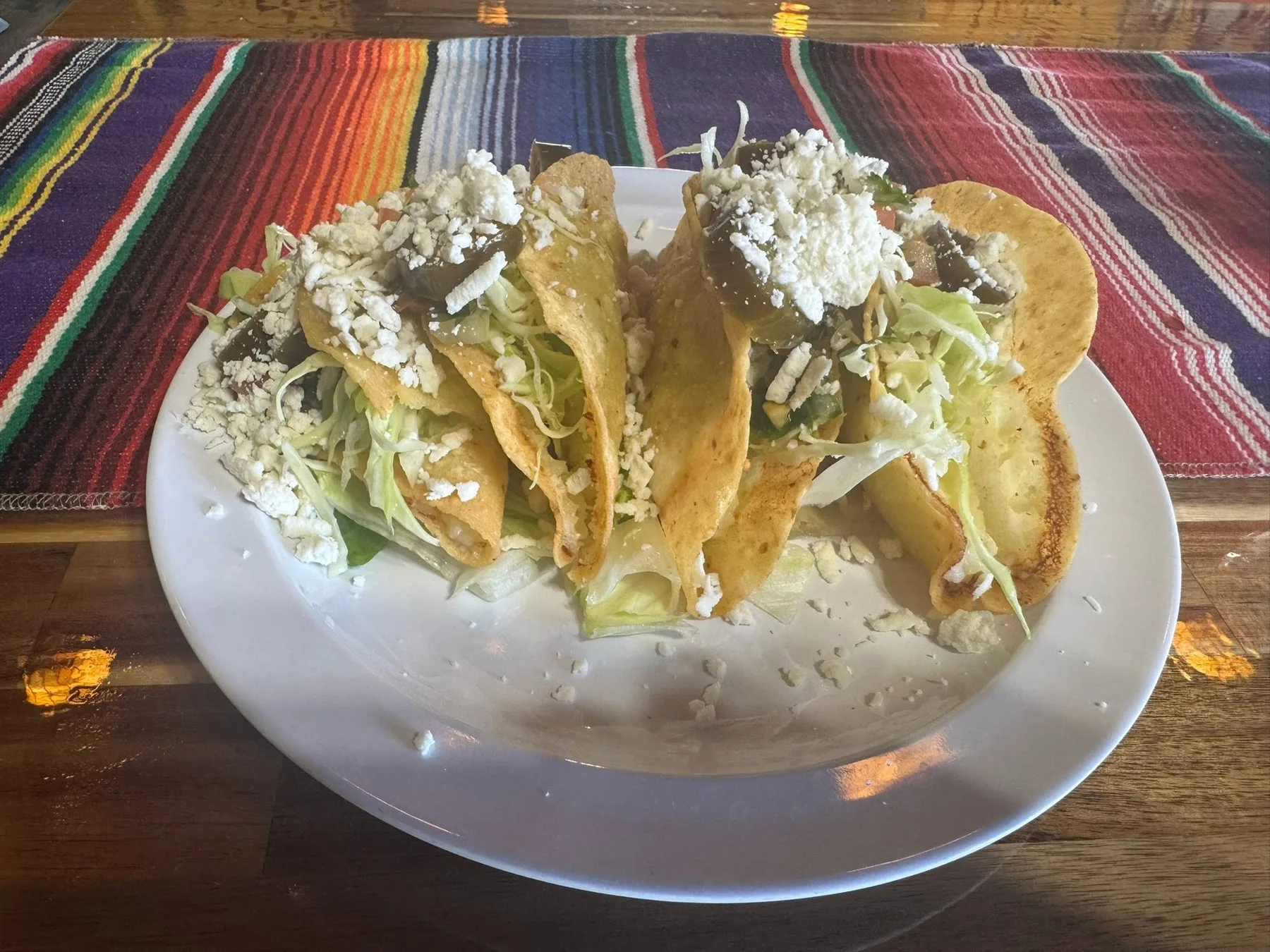 Crispy tacos topped with lettuce, crema, and cheese