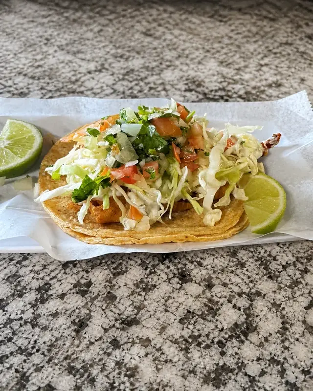 Corn tortillas with golden filling, cabbage, tomato, onion, cilantro and lime at Nina's Tacos